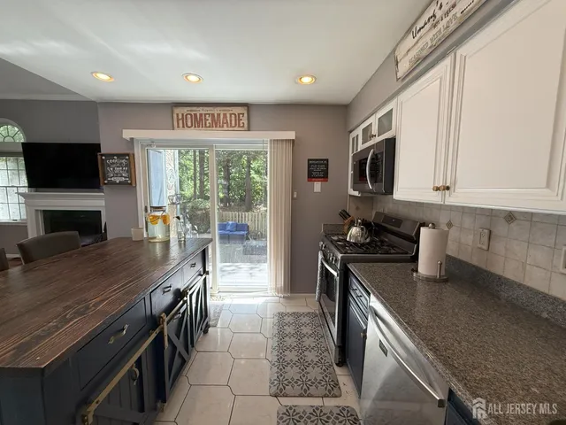 a large kitchen with stainless steel appliances granite countertop a stove top oven a sink dishwasher a dining table and chairs with wooden floor