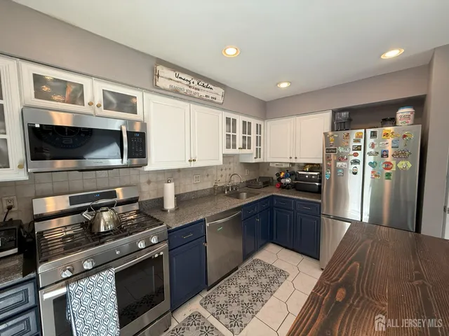 a kitchen with stainless steel appliances kitchen island granite countertop a refrigerator stove and sink