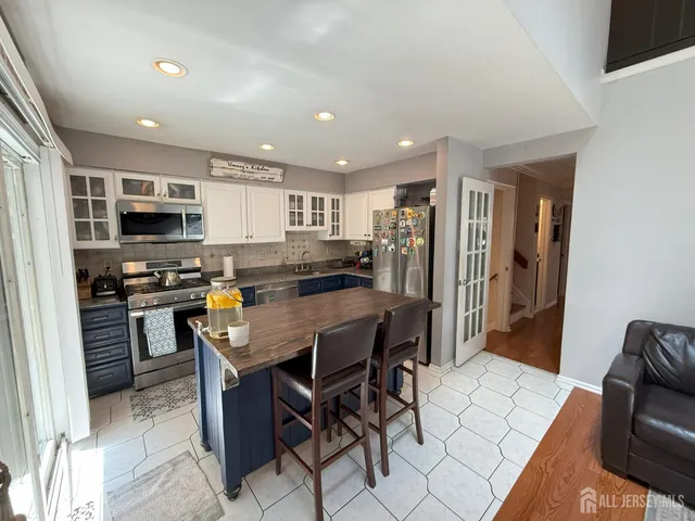 a kitchen with stainless steel appliances kitchen island granite countertop a refrigerator a stove a microwave oven a sink a dining table and chairs