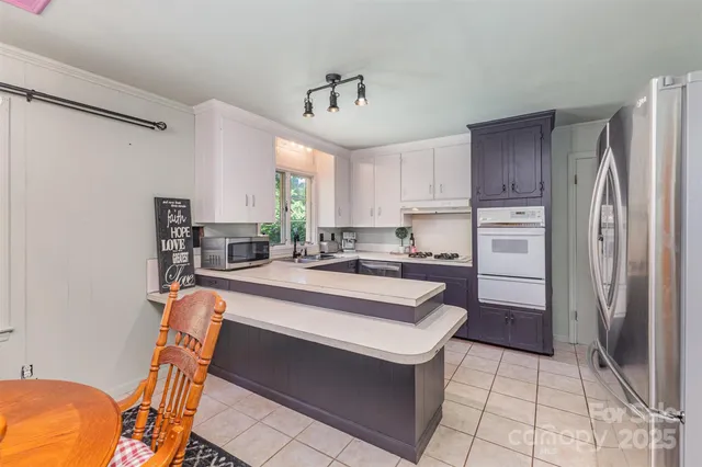 a large kitchen with kitchen island a stove a refrigerator and a dining table with wooden floor