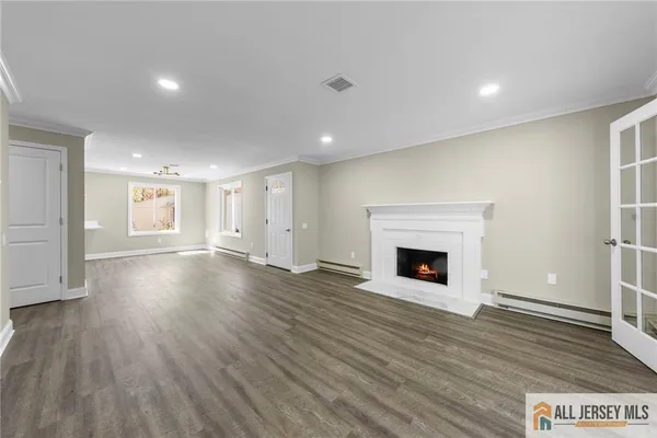 a view of an empty room with wooden floor fireplace and a window