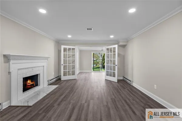 a view of an empty room with wooden floor fireplace and a window