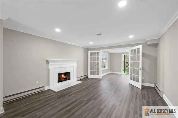 an empty room with wooden floor fireplace and windows