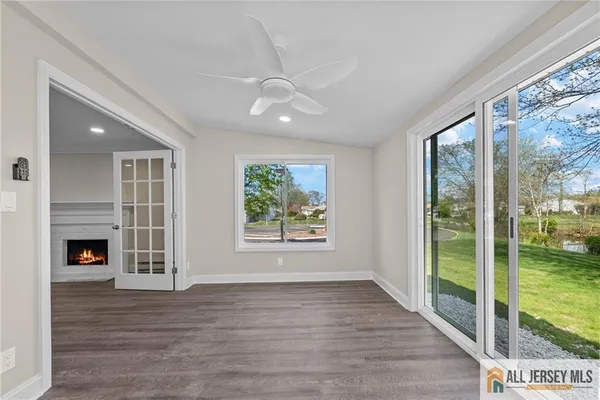 a view of an empty room with wooden floor and a fireplace