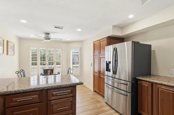 a kitchen with granite countertop a refrigerator and wooden cabinets