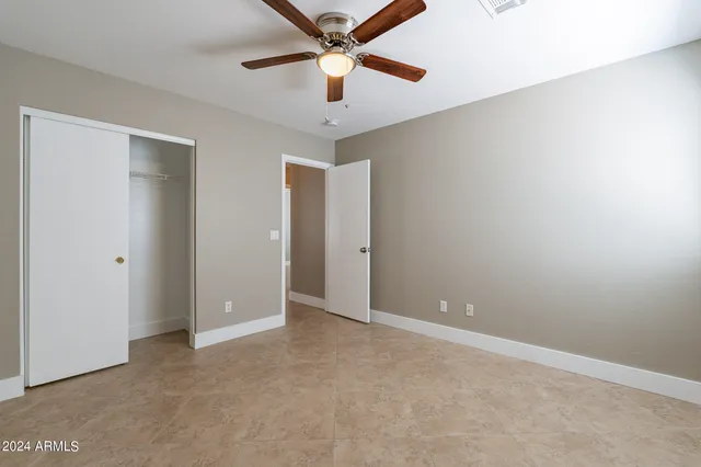 an empty room with closet and a chandelier fan