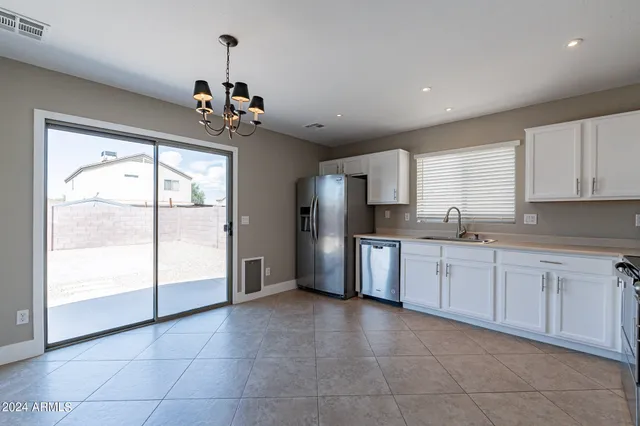 a kitchen with granite countertop a refrigerator and white cabinets