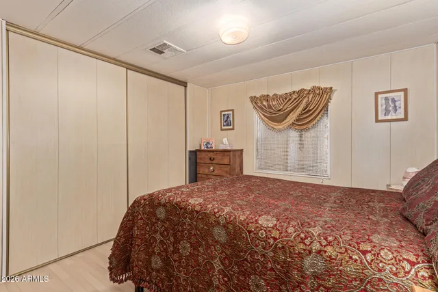 a bedroom with a bed and a lamp on the dresser