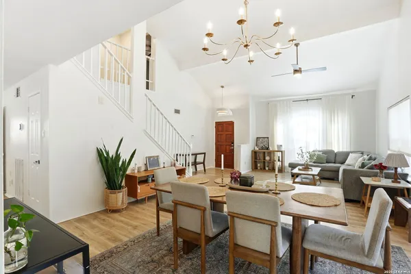 a dining room with wooden floor a potted plant and a chandelier