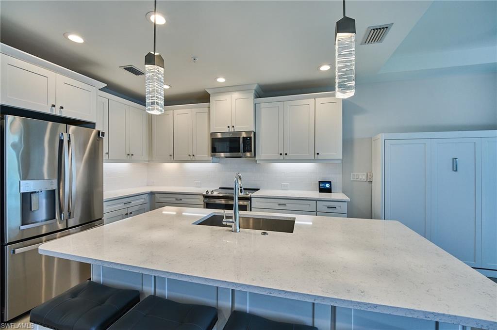 2664 Seychelles Circle, Unit 2402 Naples, FL 34112 - Photo 4 of 30 a kitchen with kitchen island a stove a sink and a refrigerator