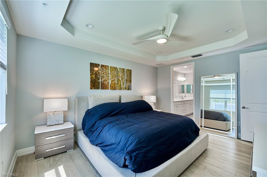 2664 Seychelles Circle, Unit 2402 Naples, FL 34112 - Photo 9 of 30 a bedroom with a large bed and a chandelier