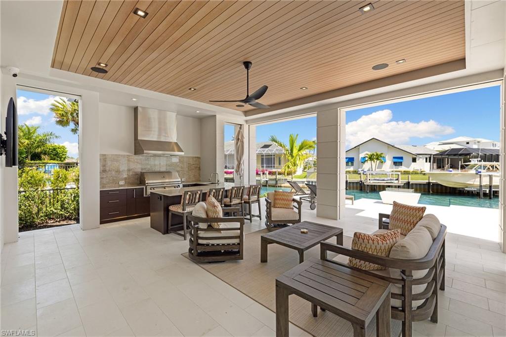 2345 Tarpon Road Naples, FL 34102 - Photo 16 of 43 View of patio / terrace featuring an outdoor kitchen and area to lounge, ceiling fan, a water view, an outdoor pool, and a residential view