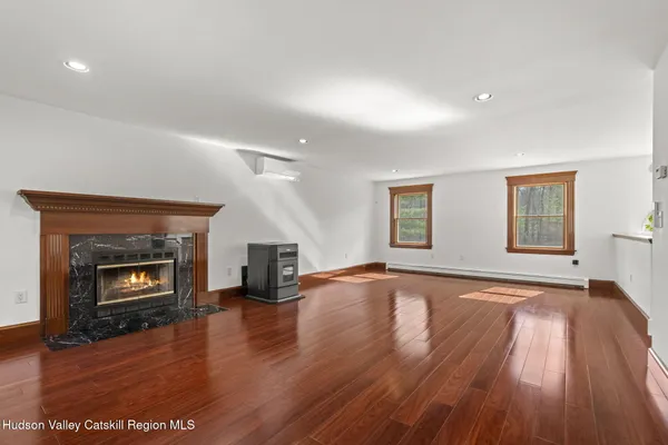 an empty room with wooden floor fireplace and windows