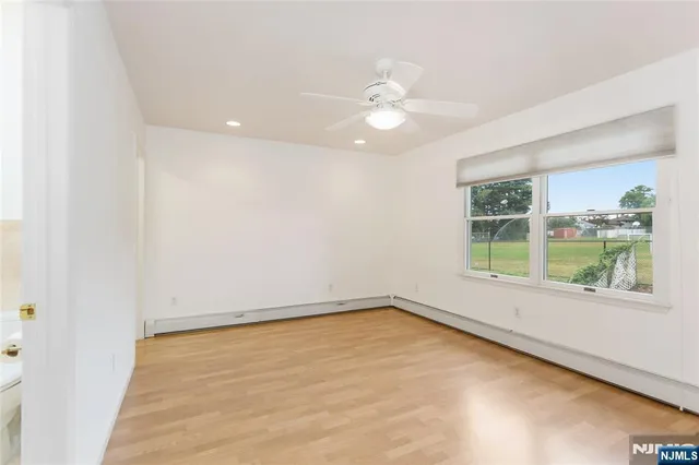 an empty room with a window and a ceiling fan