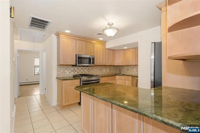 a kitchen with granite countertop white cabinets and stainless steel appliances