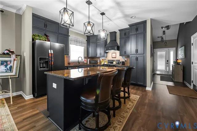 a kitchen with stainless steel appliances granite countertop a refrigerator a sink dishwasher a dining table and chairs with wooden floor