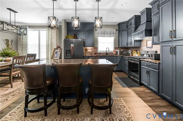 a kitchen with stainless steel appliances granite countertop a sink a stove a table and chairs