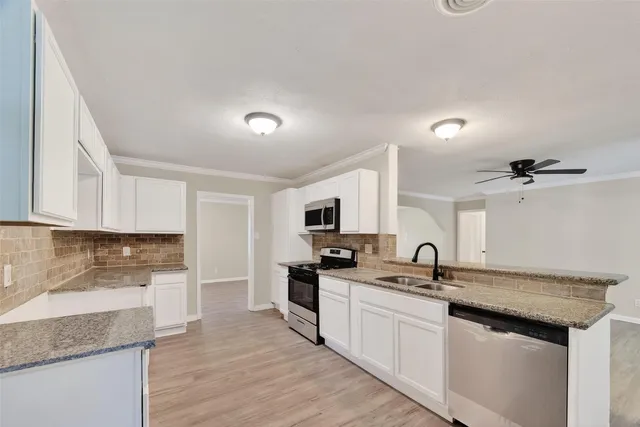a kitchen with granite countertop a sink stainless steel appliances and cabinets