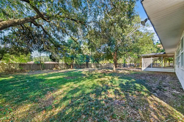 a view of a yard in front of a house with large trees