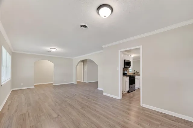 a kitchen with stainless steel appliances granite countertop a stove top oven a sink dishwasher and a refrigerator with wooden floor