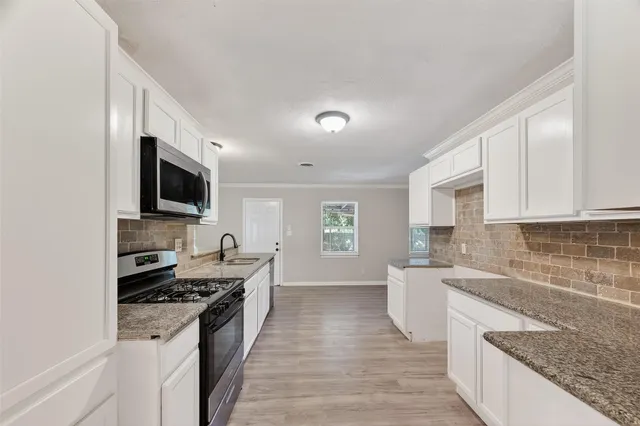 a large white kitchen with kitchen island a stove a sink and white cabinets
