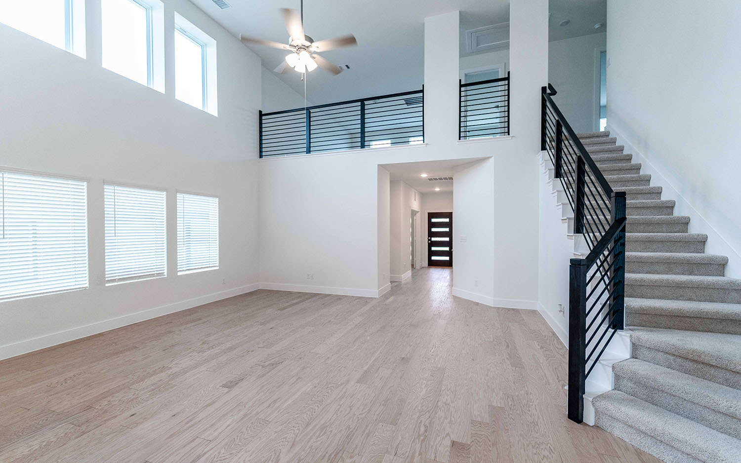 104 Old Silver Drive Jarrell, TX 76537 - Photo 4 of 19 Unfurnished living room featuring a towering ceiling, light wood-type flooring, a ceiling fan, and stairway