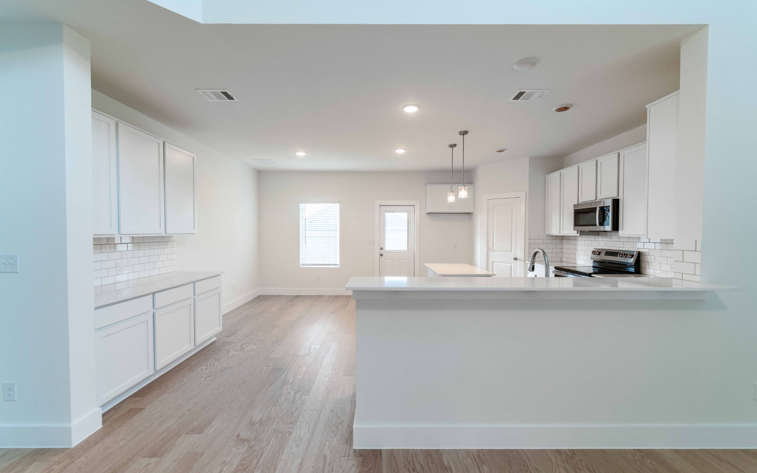 104 Old Silver Drive Jarrell, TX 76537 - Photo 6 of 19 Kitchen featuring backsplash, light wood-style flooring, a peninsula, white cabinets, and recessed lighting
