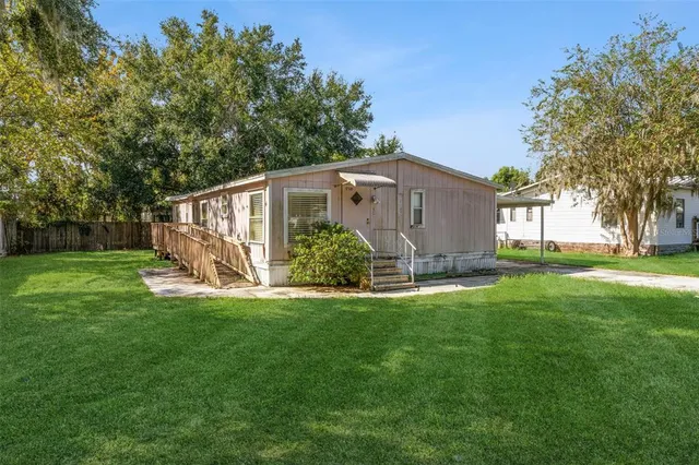 a view of a house with a big yard plants and large trees
