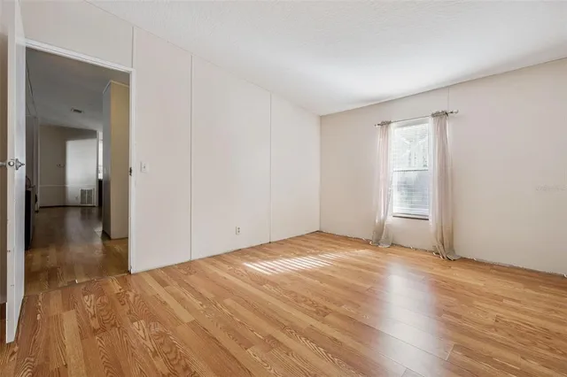 a view of an empty room with wooden floor and closet