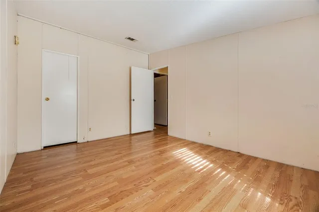 a view of an empty room with wooden floor and closet