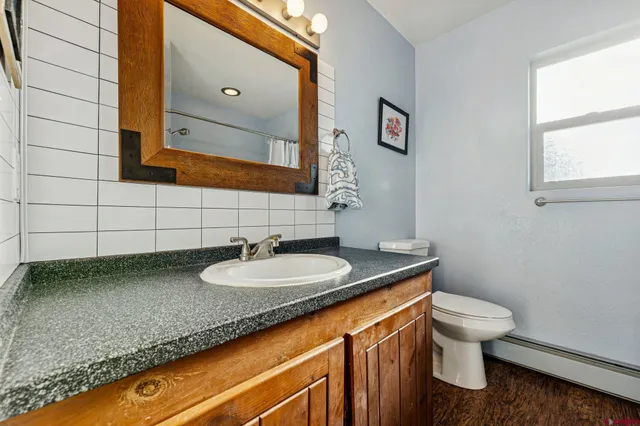 a bathroom with a granite countertop toilet sink and mirror