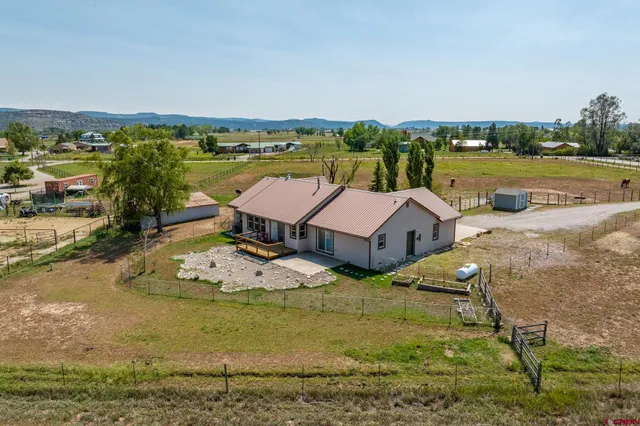 a view of a lake with lawn chairs and large trees