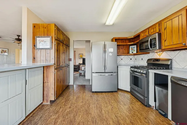 a kitchen with stainless steel appliances granite countertop a refrigerator a stove and a wooden floors
