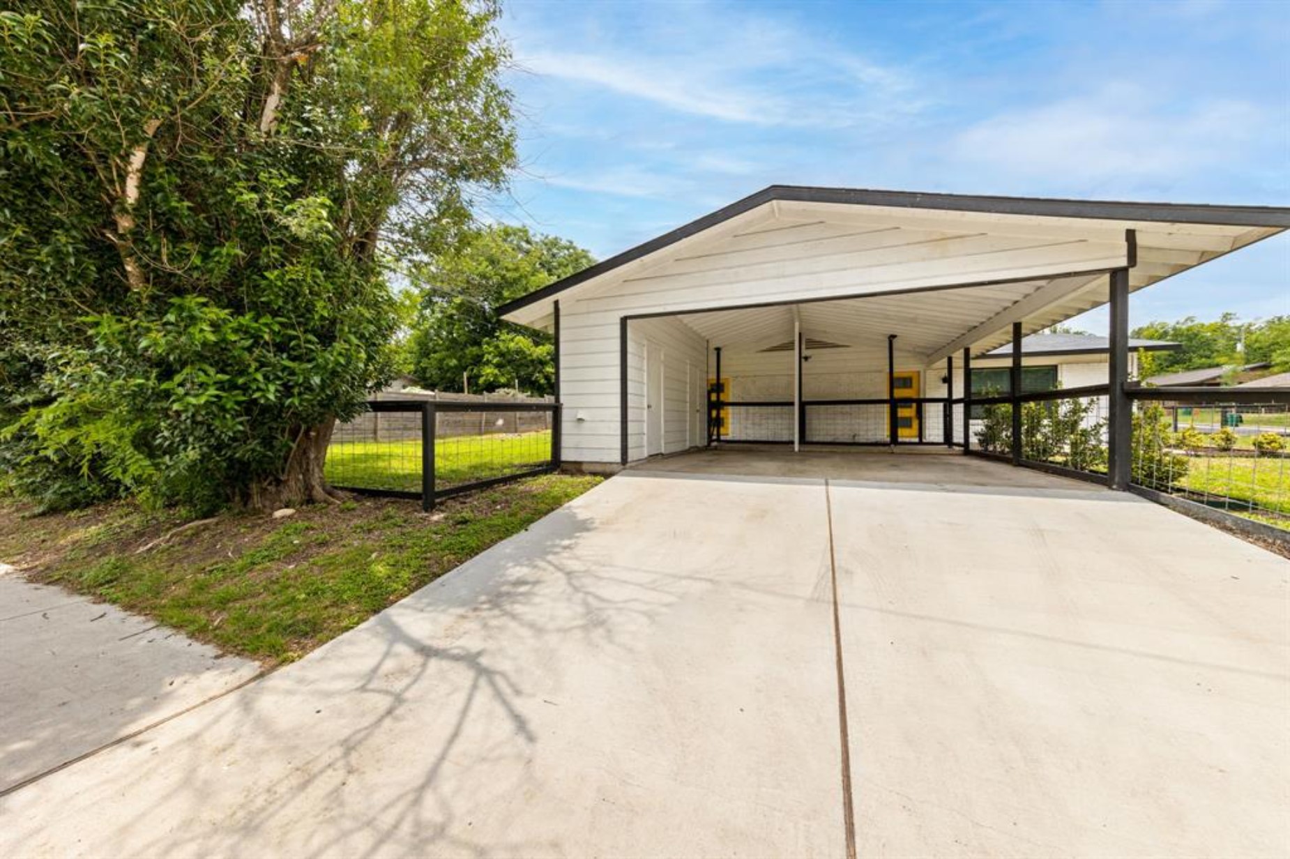 a view of backyard with large trees and flower plants