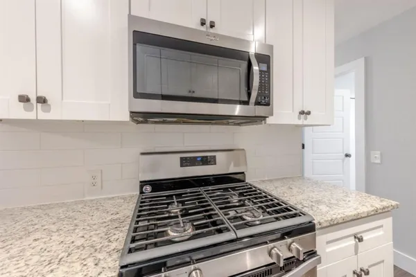 a kitchen with granite countertop a stove and a microwave
