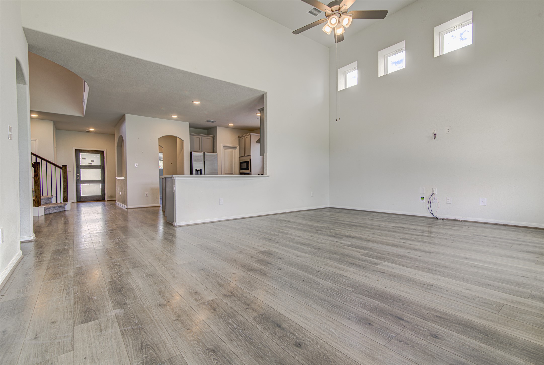774 Cherrystone Loop Buda, TX 78610 - Photo 15 of 38 The open-concept living area features tall ceilings and light wood-look flooring, extending seamlessly into the adjacent kitchen.