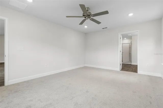 an empty room with a fan & a window