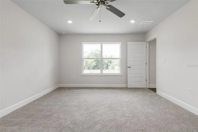 an empty room with a window and a ceiling fan
