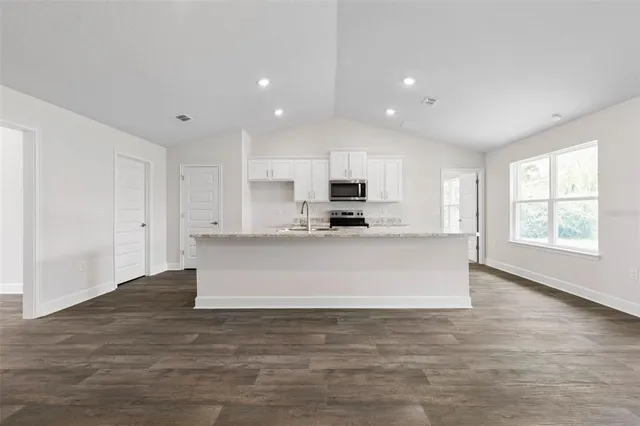 a view of kitchen with granite countertop white cabinets and window