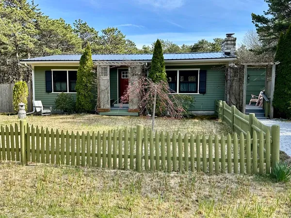 a view of a wooden house with a yard and sitting area