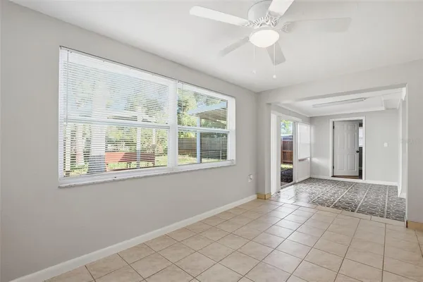 an empty room with chandelier fan and windows