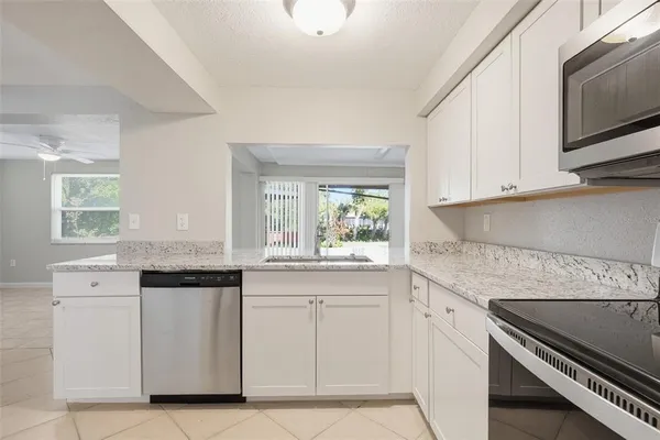 a kitchen with white cabinets appliances and a window