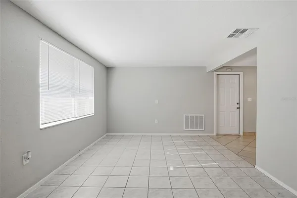 a view of an empty room with window and cabinet area