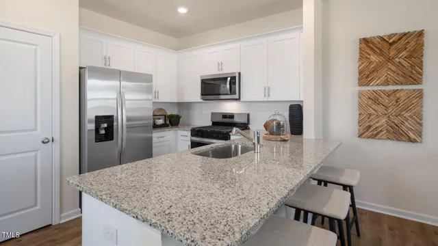 a kitchen with stainless steel appliances granite countertop a refrigerator a stove and a sink with wooden floor