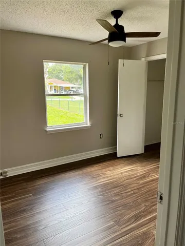 a view of an empty room with a window and wooden floor