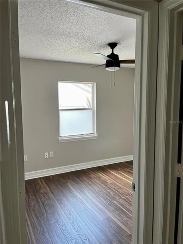 a view of empty room with wooden floor and fan
