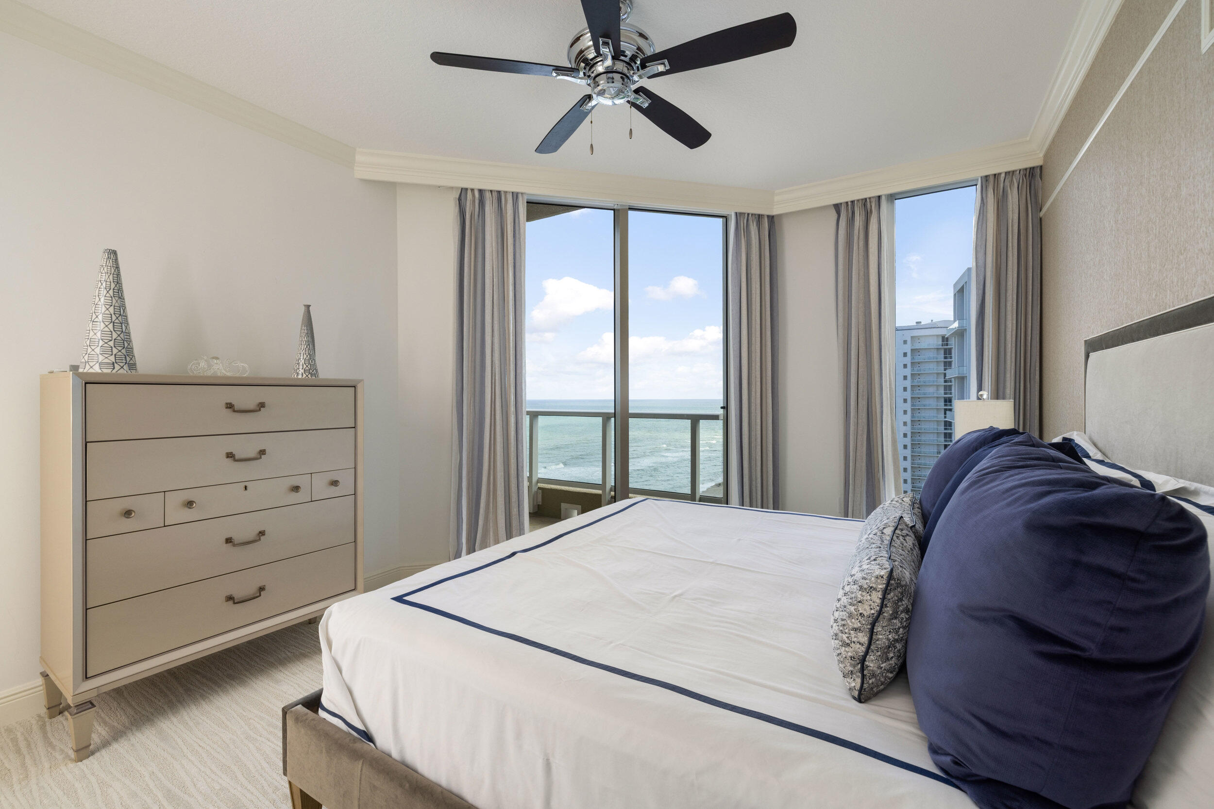 5050 North Ocean Drive, Unit 1502 Singer Island, FL 33404 - Photo 27 of 56 a bedroom with a bed a window and a chandelier