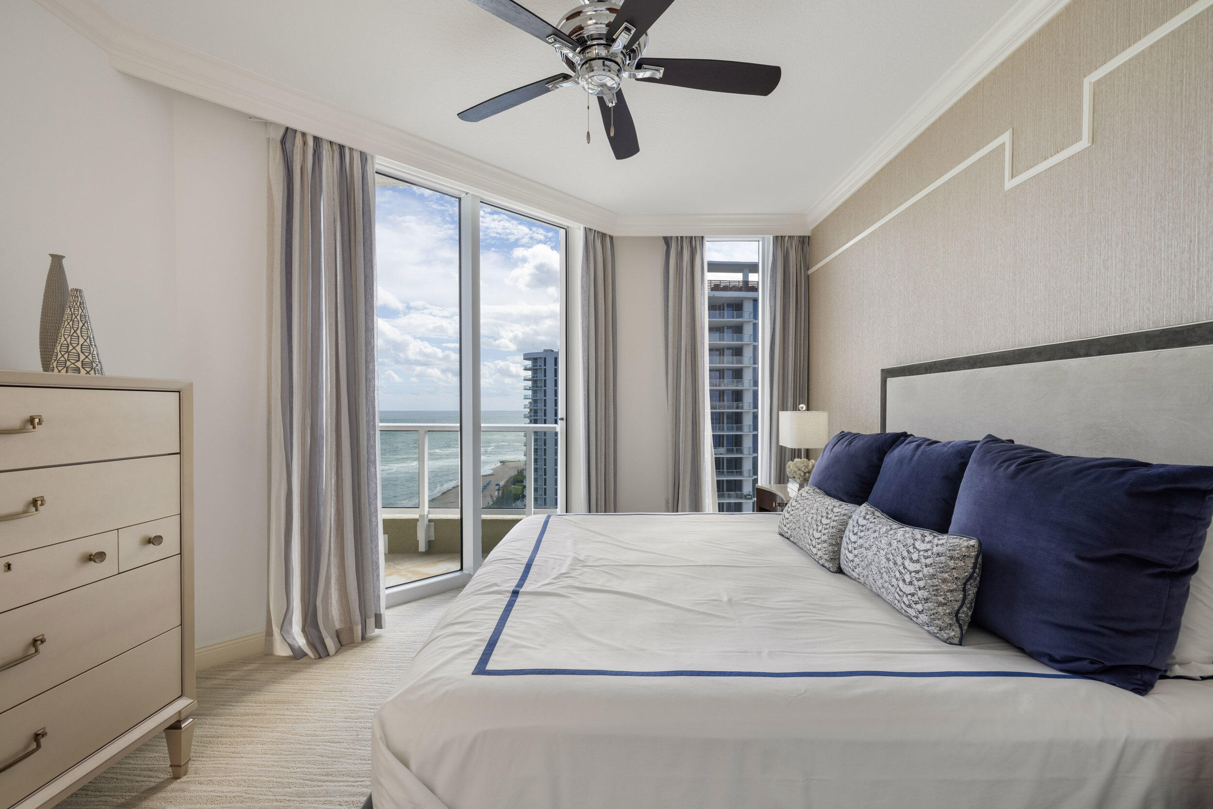 5050 North Ocean Drive, Unit 1502 Singer Island, FL 33404 - Photo 28 of 56 a bedroom with a large bed and a chandelier fan