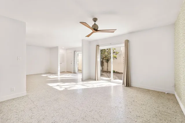 an empty room with a kitchen space and a ceiling fan