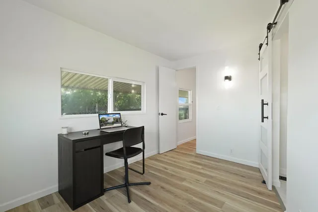 a view of a workspace with wooden floor and a window